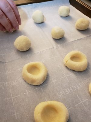 Holiday Pecan Thumbprint Cookies Recipe, Putting thumbprint sugar cookie dough onto a sheet pan