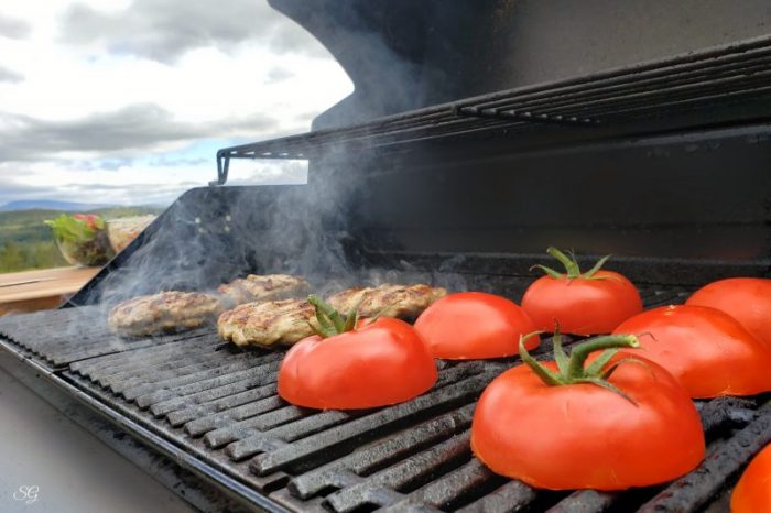 Grilled Turkey Burgers with Tomato Buns, Grilling turkey burgers and tomatoes for buns the barbecue grill.