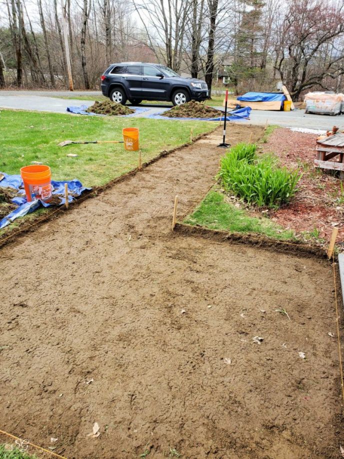 How To Install A DIY Paver Walkway, Using a hand tamper to compact the soil.