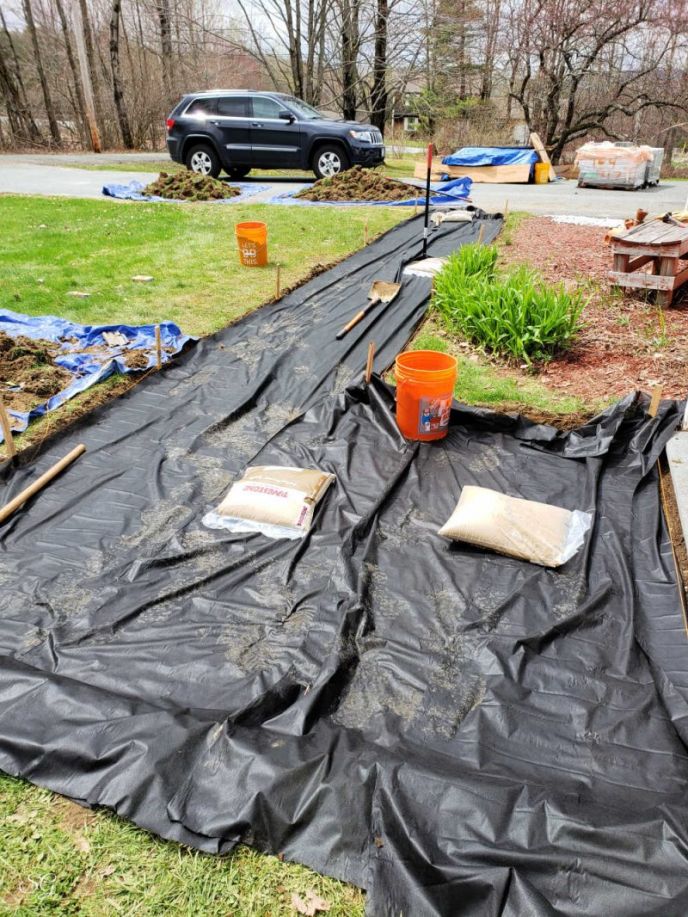 How To Install A DIY Paver Walkway, Putting down landscape fabric under the sand of our paver walkway DIY project.