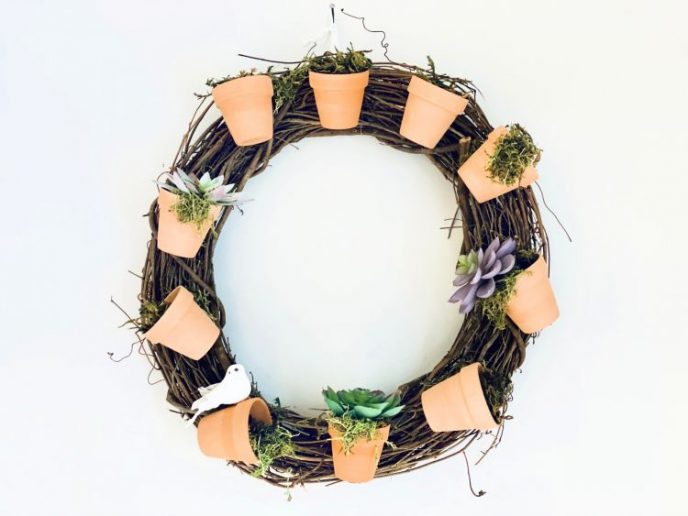 Succulent wreath completed hanging on a white wall.