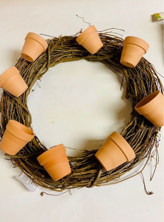 Dry fitting the terracotta pots onto the grapevine wreath before gluing them into position.